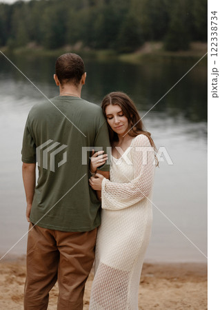 Caucasian heterosexual couple hugging by peaceful lake shore Caucasian heterosexual couple hugging by peaceful lake shore 122338734