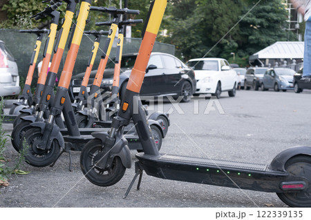 Electric scooters in a row in a parking lot. 122339135