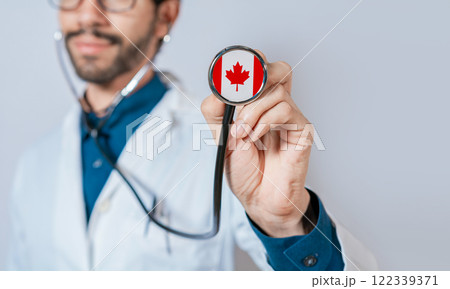 Doctor holding stethoscope with Canada flag. Canadian Health and Care Concept, Canada flag on stethoscope 122339371