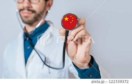 Doctor holding stethoscope with China flag. Chinese Health and Care Concept, China flag on stethoscope Doctor holding stethoscope with China flag. Chinese Health and Care Concept, China flag on stethoscope 122339372