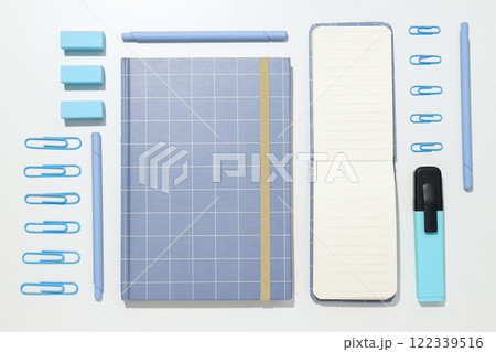 A checkered notebook with stationery on a white background A checkered notebook with stationery on a white background 122339516