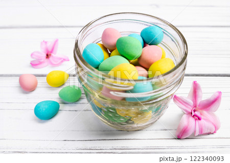 Easter decor with a jar with sweet eggs and hyacinth flowers. 122340093