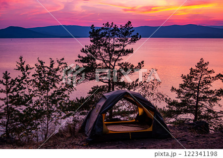 Tent on a hill near the lake against the backdrop of a picturesque sunset 122341198