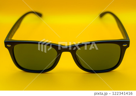 Black sunglasses with dark lenses on yellow background 122341416