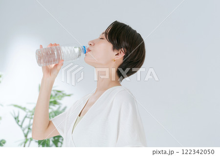 ペットボトルの水を飲むトレーニングウェアの女性 122342050