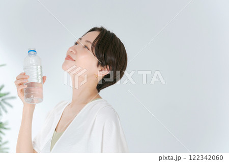 ペットボトルの水を飲むトレーニングウェアの女性 122342060