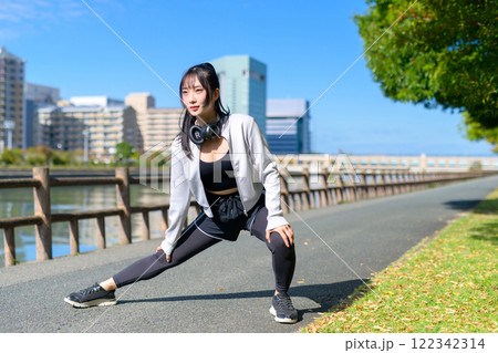 川沿いの歩道で脚のストレッチをするかっこいい女性　歩く　ダイエット　散歩　運動　 122342314