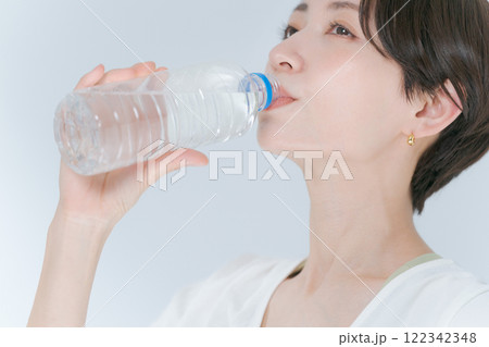 ペットボトルの水を飲むトレーニングウェアの女性 ペットボトルの水を飲むトレーニングウェアの女性 122342348
