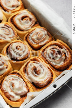 Freshly baked cinnamon rolls drizzled with icing in a baking pan Freshly baked cinnamon rolls drizzled with icing in a baking pan 122343320