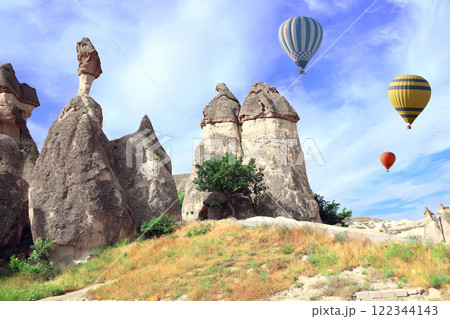 The balloon flight, famous tourist attraction of Cappadocia. Air balloons and Fairy Chimney (multihead stone mushrooms) in Pasabag Valley, Cappadocia, Anatolia, Turkey 122344143