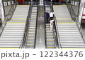 People ascending an escalator in a modern railway station. Bright, spacious public space with polished metal railings, organized infrastructure, and bustling transit movement. 122344376