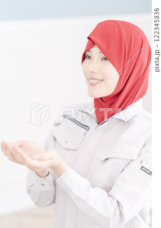 会社の礼拝室でお祈りをする作業着姿の若い女性 122345836