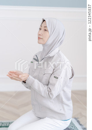 会社の礼拝室でお祈りをする作業着のミドルの女性 122345837