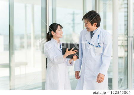病院の通路で話す医者・医師・医療従事者・ドクター・薬剤師・科学者・研究員の男女 122345864