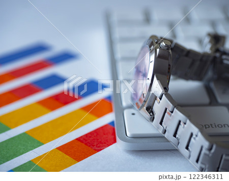 テーブルに置かれたグラフとキーボードと腕時計 122346311