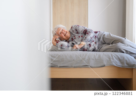 Elderly woman receiving a joyful wake up phone call from friend, lying in bed. Elderly woman receiving a joyful wake up phone call from friend, lying in bed. 122346881