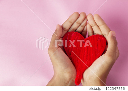 Woman's hand holding red heart, knitted red heart isolated on pink background 122347256
