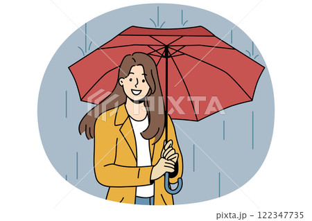Happy woman with umbrella walks in rain along autumn street and looks at screen with wide smile 122347735