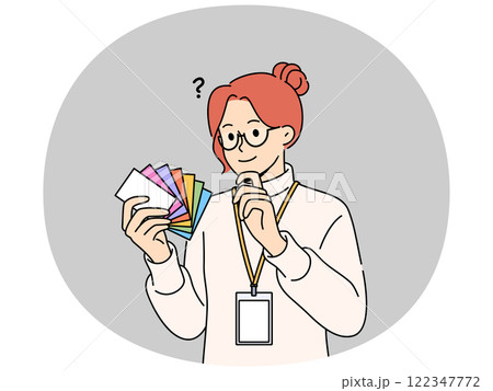 Woman designer holds palette of cards of different colors, choosing desired shade to use in design Woman designer holds palette of cards of different colors, choosing desired shade to use in design 122347772