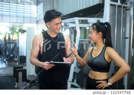 Fitness coach offering advice and guidance to his client in a modern gym. Fitness coach offering advice and guidance to his client in a modern gym. 122347788