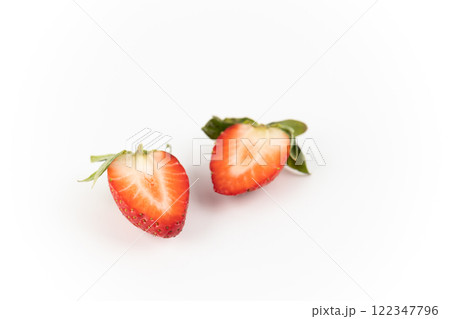 on white photo background there are cut two halves of one ripe strawberry, healthy vitamins, seasonal summer fruit, vitamin C green strawberry tail like a crown 122347796