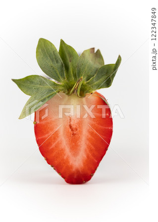 close up on white photo background there is a cut half of a ripe strawberry suspended in the air healthy vitamins seasonal summer fruit vitamin C green strawberry tail like a crown close up on white photo background there is a cut half of a ripe strawberry suspended in the air healthy vitamins seasonal summer fruit vitamin C green strawberry tail like a crown 122347849