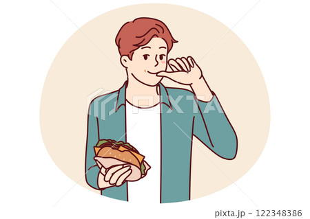 Man with burger licks fingers and enjoys reception of fast food bought in street restaurant 122348386