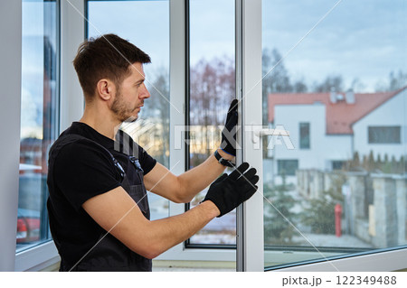 Professional repairman adjusting white pvc windows in modern building. Construction worker installing plastic window in new home. Concept of repair and maintenance Professional repairman adjusting white pvc windows in modern building. Construction worker installing plastic window in new home. Concept of repair and maintenance 122349488
