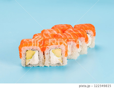 Studio photography of Philadelphia Roll of velvety cream cheese, and avocado, wrapped in perfect seasoned sushi rice and fresh salmon. Isolated on solid light blue background 122349815