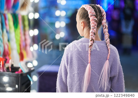 A child with pigtails made of pink kanekalon. Showing off her braided hair. There is a place to copy. High quality photo 122349840