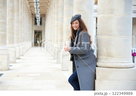 Stylish woman enjoying coffee in Parisian colonnade.  122349989