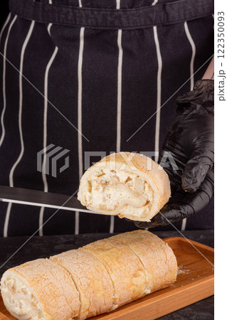 dessert meringue roll with fresh pear on a dark background in a 122350093