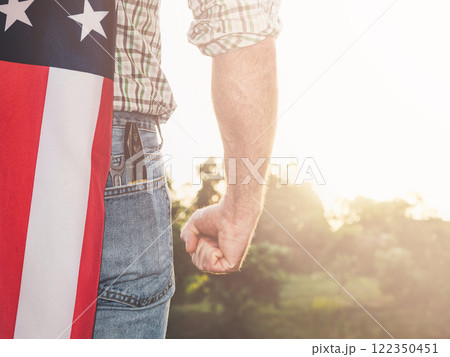 Attractive man in work clothes, holding American Flag 122350451