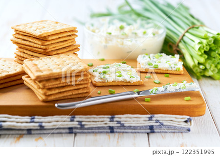 Biscuits with a cream cheese spread and freshly cut chives on a wooden cutting board, selective focus. 122351995