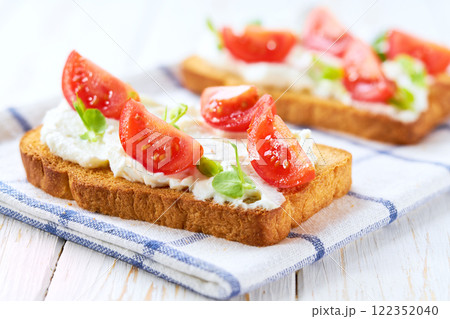Healthy breakfast, bruschetta with ricotta cheese, and cherry tomatoes on a kitchen table. 122352040