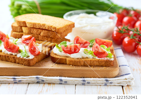 Healthy breakfast, bruschetta with ricotta cheese, and cherry tomatoes on a kitchen table. 122352041