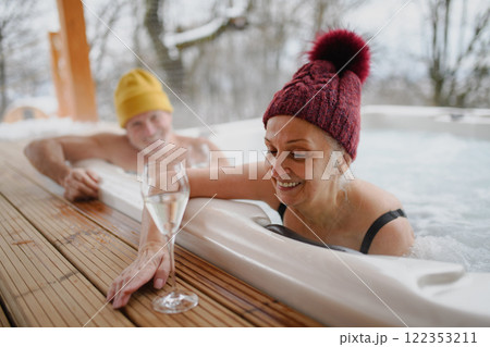 Lovely seniors drinking champagne while bathing in hot tub during. Romantic wellness getaway with spa during Valentine's weekend. 122353211