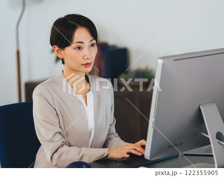 暗いオフィスでパソコンを使って作業する女性ビジネスパーソン 暗いオフィスでパソコンを使って作業する女性ビジネスパーソン 122355905