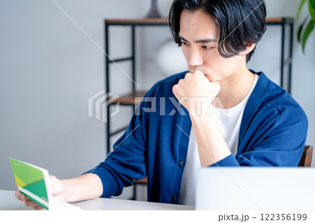 通帳を見つめる男性 通帳を見つめる男性 122356199