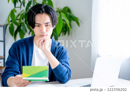 通帳を見つめる男性 通帳を見つめる男性 122356202
