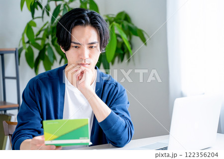 通帳を見つめる男性 通帳を見つめる男性 122356204