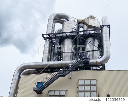 Industrial facility with large metal structures, pipes, and cylindrical containers. 122356229
