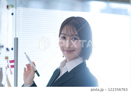 ホワイトボードに書き込みする若いビジネスウーマン ホワイトボードに書き込みする若いビジネスウーマン 122356763