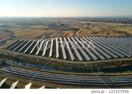 Aerial view of large sustainable electrical power plant with rows of solar photovoltaic panels for producing clean ecological electric energy. Renewable electricity with zero emission concept Aerial view of large sustainable electrical power plant with rows of solar photovoltaic panels for producing clean ecological electric energy. Renewable electricity with zero emission concept 122357048