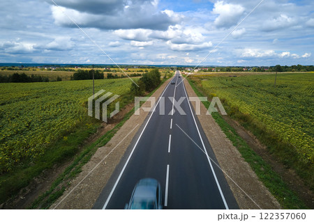 Aerial view of intercity road between green agricultural fields with fast driving cars. Top view from drone of highway traffic 122357060