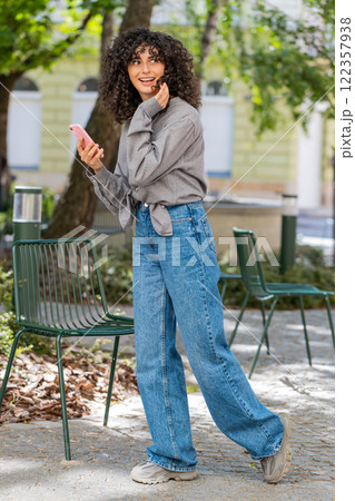 Tourist young curly hair woman using smartphone typing text messages looking for search a way on map Tourist young curly hair woman using smartphone typing text messages looking for search a way on map 122357938