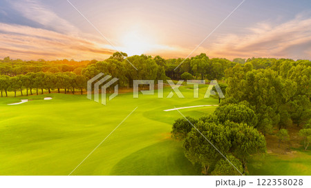 A serene sunset view of a golf course surrounded by lush greenery A serene sunset view of a golf course surrounded by lush greenery 122358028