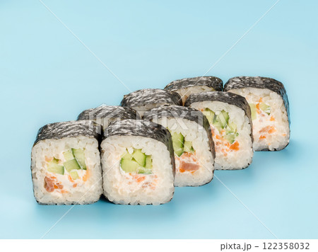 Studio photography of Maki roll with cucumber and salmon mousse wrapped in nori. Isolated on solid light blue background 122358032