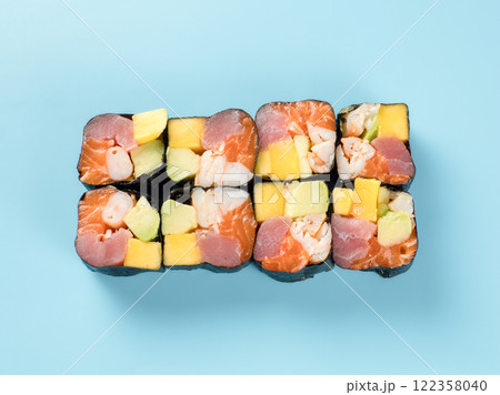 Top view of Hawaiian roll with mango, avocado, shrimp, salmon and tuna. Studio photography of colorful Hawaiian maki roll with shrimp, salmon and tuna. Isolated on solid light blue background. 122358040