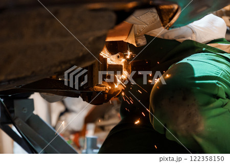 Skilled Mechanic Performing Precision Metalwork with Sparks Flying in Automotive Workshop Skilled Mechanic Performing Precision Metalwork with Sparks Flying in Automotive Workshop 122358150